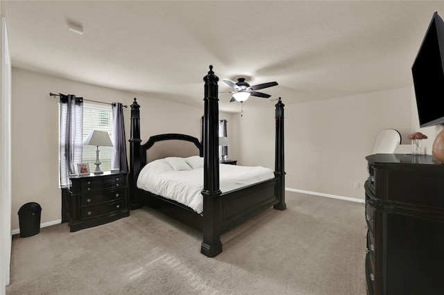 bedroom featuring a textured ceiling, light colored carpet, and ceiling fan