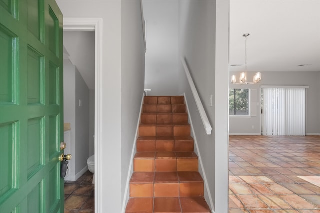 staircase with an inviting chandelier