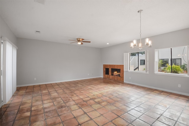 unfurnished living room with ceiling fan with notable chandelier and a tiled fireplace