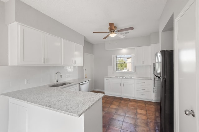 kitchen featuring sink, backsplash, kitchen peninsula, black refrigerator, and white cabinets