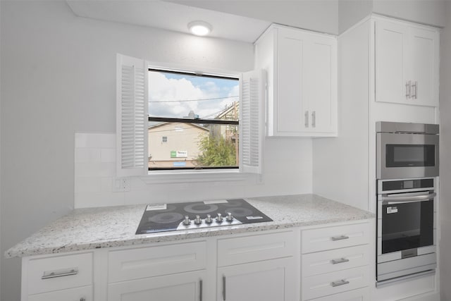 kitchen featuring backsplash, white cabinets, black electric cooktop, double oven, and light stone counters