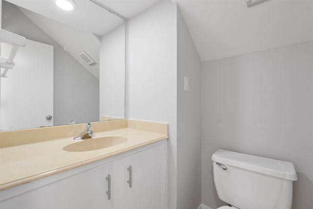 bathroom with vanity, toilet, and lofted ceiling