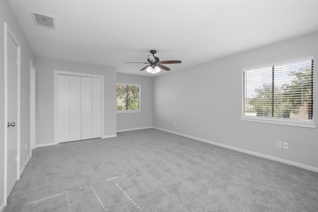 unfurnished bedroom featuring ceiling fan, a closet, and light carpet