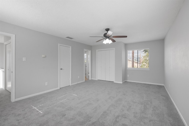 unfurnished bedroom featuring a textured ceiling, ceiling fan, and light carpet