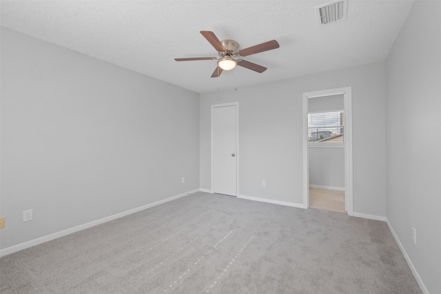 unfurnished bedroom with ceiling fan, light colored carpet, a textured ceiling, and a closet