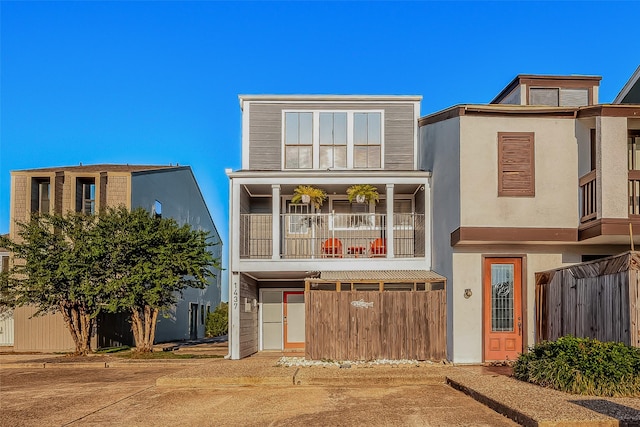 view of front of home featuring stucco siding, a balcony, and fence