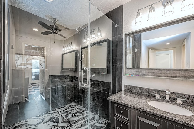 bathroom with a shower stall, a textured ceiling, vanity, and ceiling fan