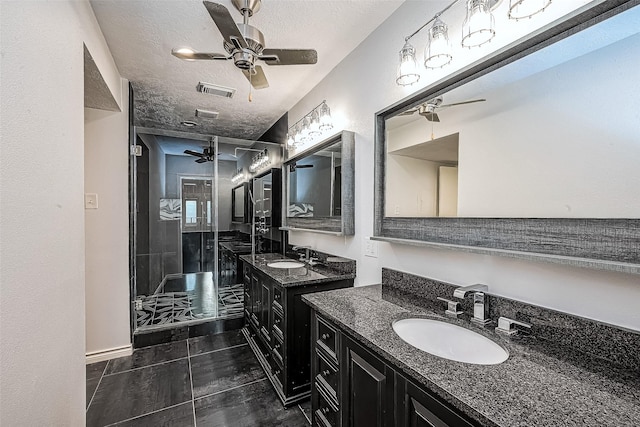 bathroom featuring a textured ceiling, two vanities, a ceiling fan, and a sink