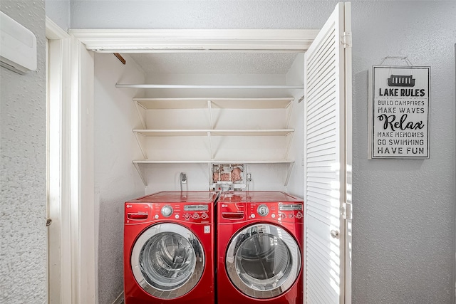 clothes washing area with a textured wall, laundry area, and washing machine and clothes dryer