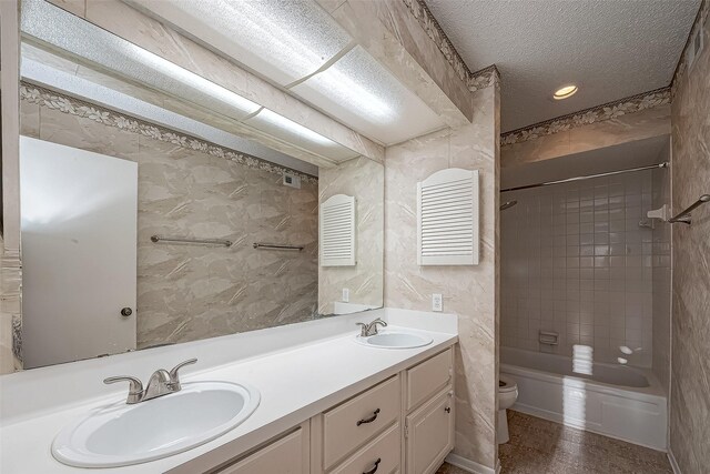 bathroom featuring double vanity, toilet, a textured ceiling, and a sink