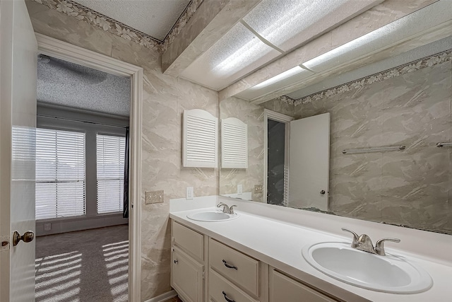 bathroom featuring a sink, a textured ceiling, and double vanity