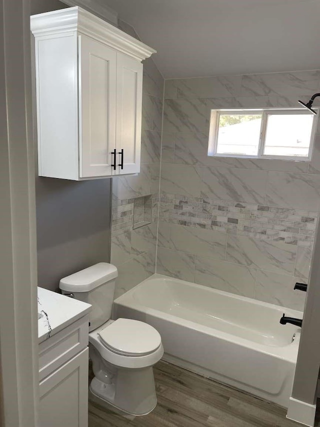 full bathroom with tiled shower / bath combo, toilet, wood-type flooring, and vanity