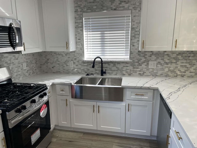 kitchen with appliances with stainless steel finishes, light hardwood / wood-style floors, and white cabinetry