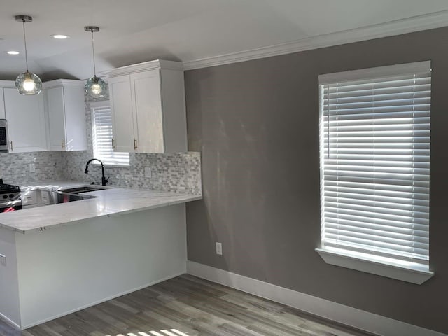 kitchen featuring light stone countertops, hanging light fixtures, tasteful backsplash, kitchen peninsula, and white cabinets