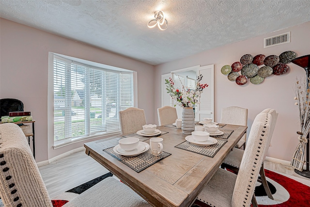 dining room with hardwood / wood-style floors and a textured ceiling