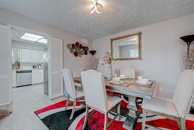 dining room with a textured ceiling and light hardwood / wood-style flooring