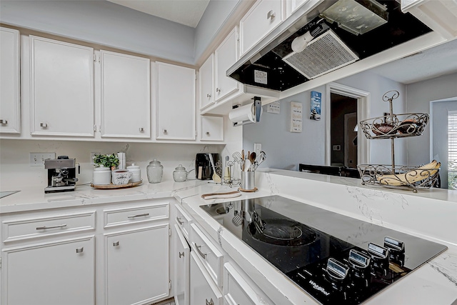 kitchen with white cabinets, black electric cooktop, and light stone counters