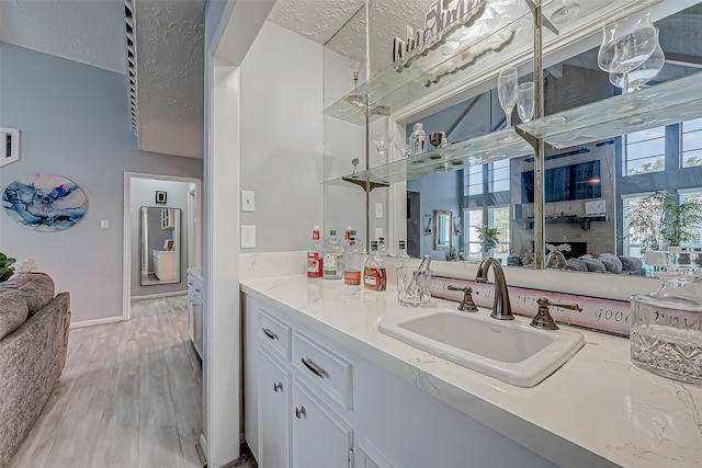 kitchen with light stone countertops, light hardwood / wood-style flooring, white cabinets, and sink