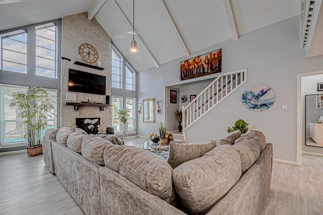 living room featuring high vaulted ceiling, a large fireplace, a wealth of natural light, and light hardwood / wood-style flooring