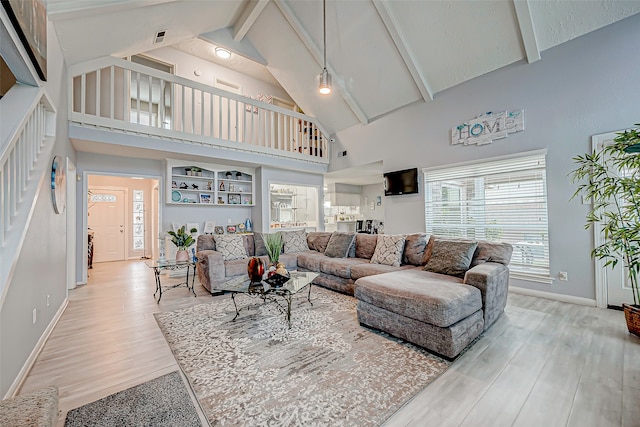 living room with light hardwood / wood-style floors, beam ceiling, and high vaulted ceiling