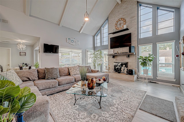 living room with a wealth of natural light, a fireplace, high vaulted ceiling, and light wood-type flooring