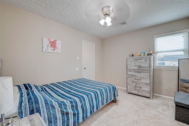 bedroom featuring carpet flooring, ceiling fan, and a textured ceiling