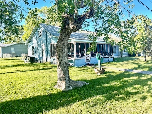 back of property with a sunroom, central AC, and a lawn