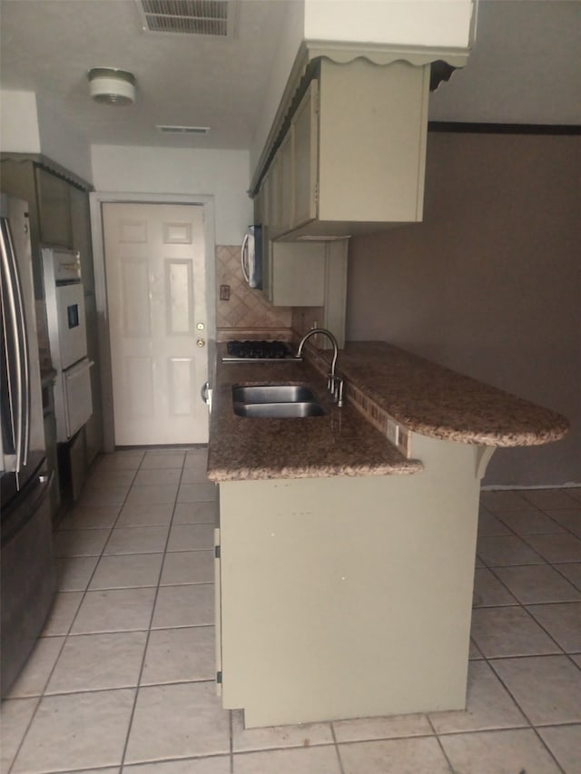 kitchen with light tile patterned floors, stainless steel appliances, green cabinets, and sink