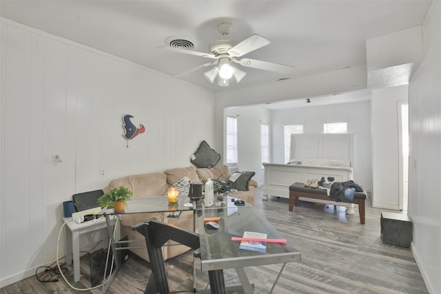 living room featuring ceiling fan, wooden walls, and hardwood / wood-style flooring