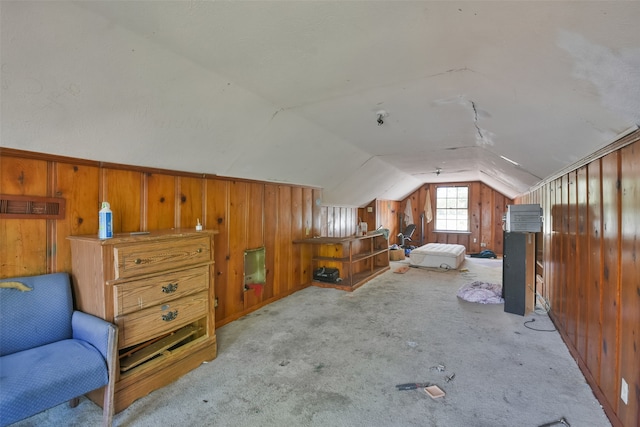 bedroom with light colored carpet, vaulted ceiling, and wood walls