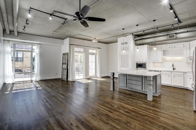 kitchen with stainless steel microwave, a healthy amount of sunlight, hanging light fixtures, a breakfast bar, and white cabinets