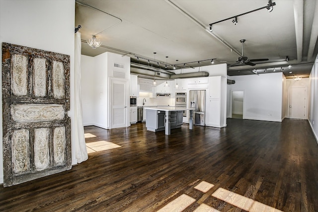 unfurnished living room featuring rail lighting, ceiling fan, dark wood-type flooring, and sink