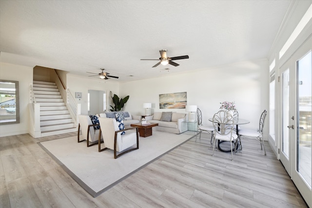 living room featuring light hardwood / wood-style floors, ceiling fan, and crown molding