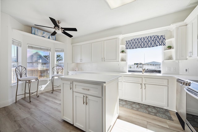 kitchen with white cabinets, ceiling fan, light hardwood / wood-style floors, and sink