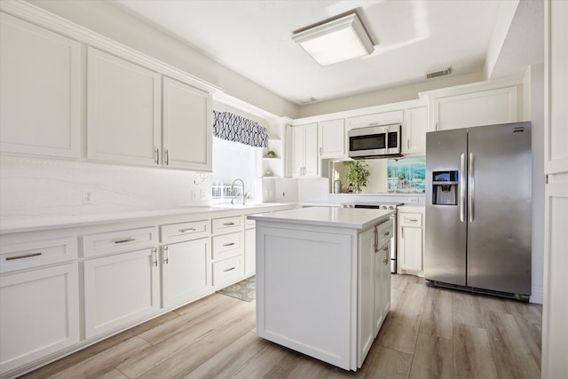 kitchen with a center island, sink, light hardwood / wood-style flooring, white cabinetry, and stainless steel appliances