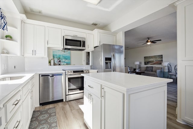 kitchen featuring white cabinetry, ceiling fan, stainless steel appliances, light hardwood / wood-style flooring, and a kitchen island