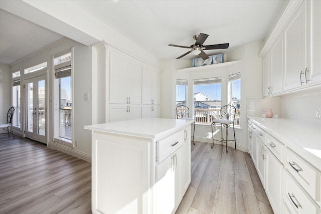 kitchen with white cabinets, a center island, and light hardwood / wood-style flooring