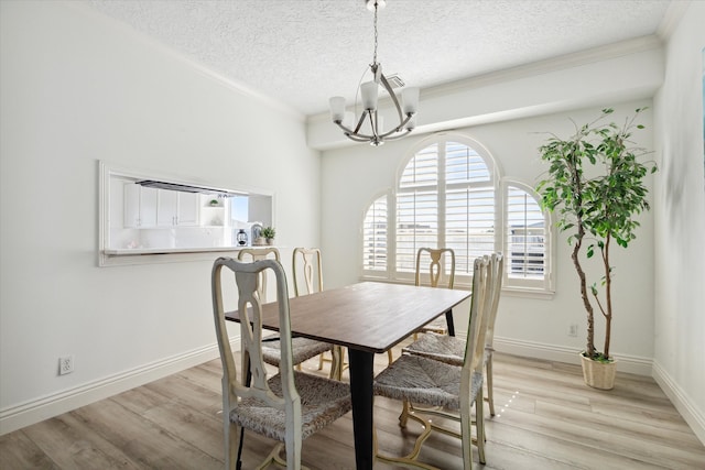 dining room with light wood-type flooring, a textured ceiling, and a notable chandelier