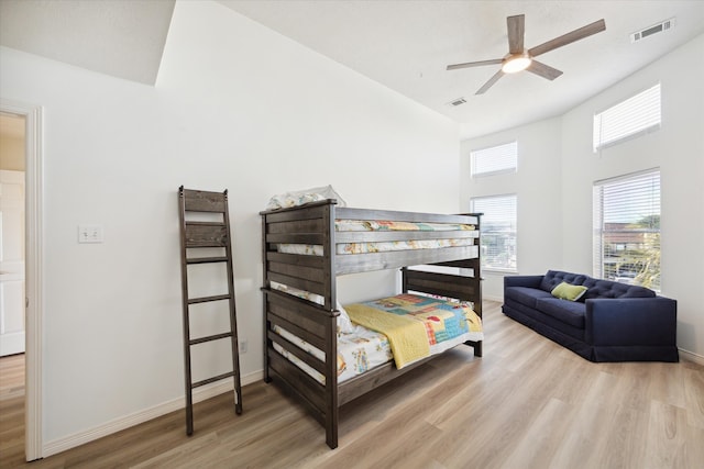 bedroom featuring a high ceiling, light hardwood / wood-style flooring, and ceiling fan