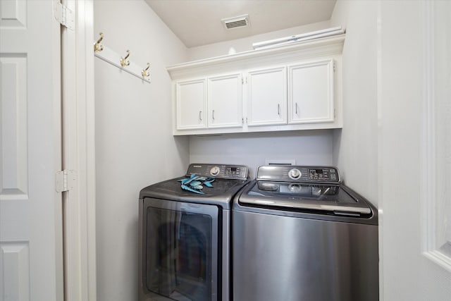 clothes washing area featuring cabinets and independent washer and dryer