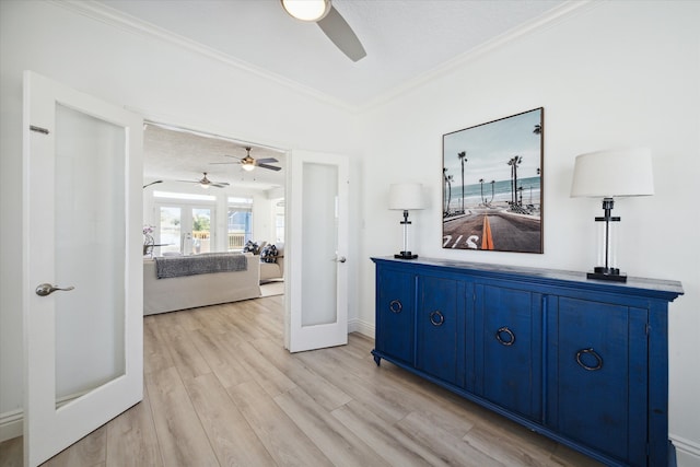 corridor featuring french doors, light wood-type flooring, a textured ceiling, and crown molding