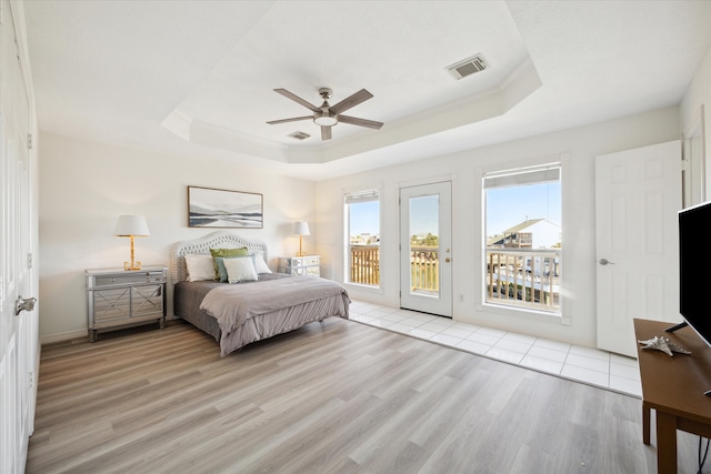 bedroom with a raised ceiling, access to outside, light hardwood / wood-style flooring, and ceiling fan