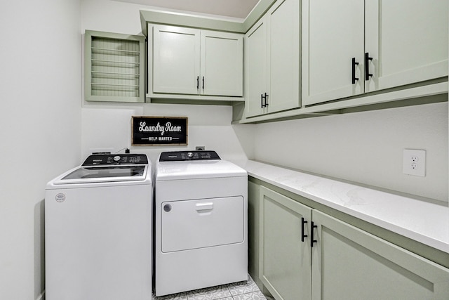 laundry room featuring washing machine and dryer, light tile patterned floors, and cabinets