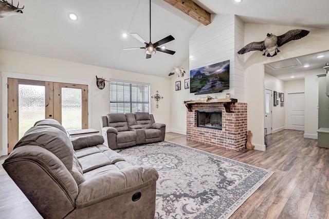 living room with beam ceiling, ceiling fan, a brick fireplace, high vaulted ceiling, and hardwood / wood-style flooring