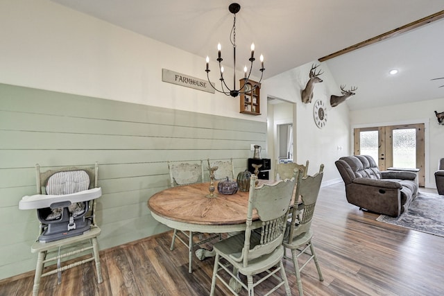 dining space with hardwood / wood-style floors, an inviting chandelier, and wooden walls