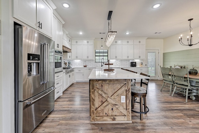 kitchen with pendant lighting, a center island, dark wood-type flooring, white cabinets, and appliances with stainless steel finishes