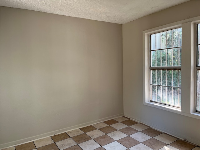 tiled spare room with a textured ceiling