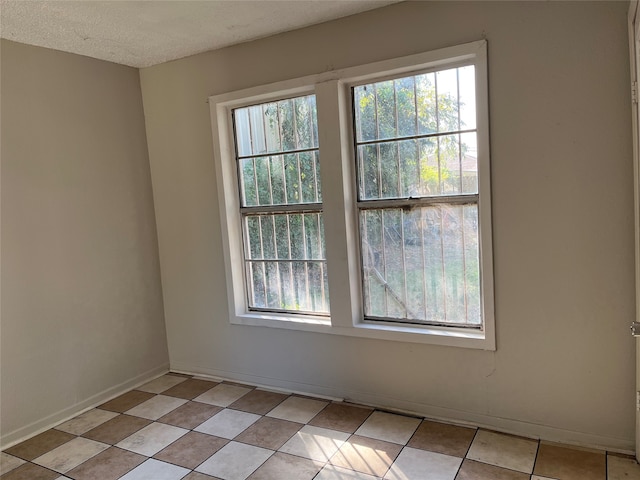 tiled spare room featuring a textured ceiling