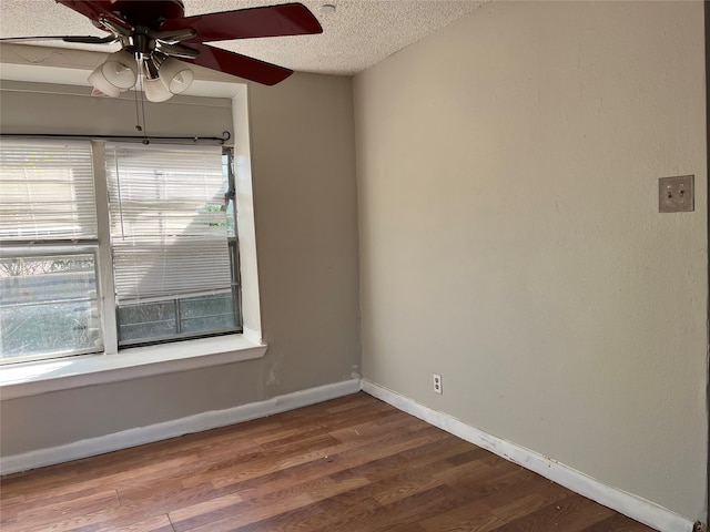 empty room with hardwood / wood-style floors, a textured ceiling, a wealth of natural light, and ceiling fan