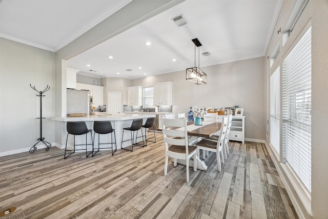 dining area with light hardwood / wood-style floors and ornamental molding